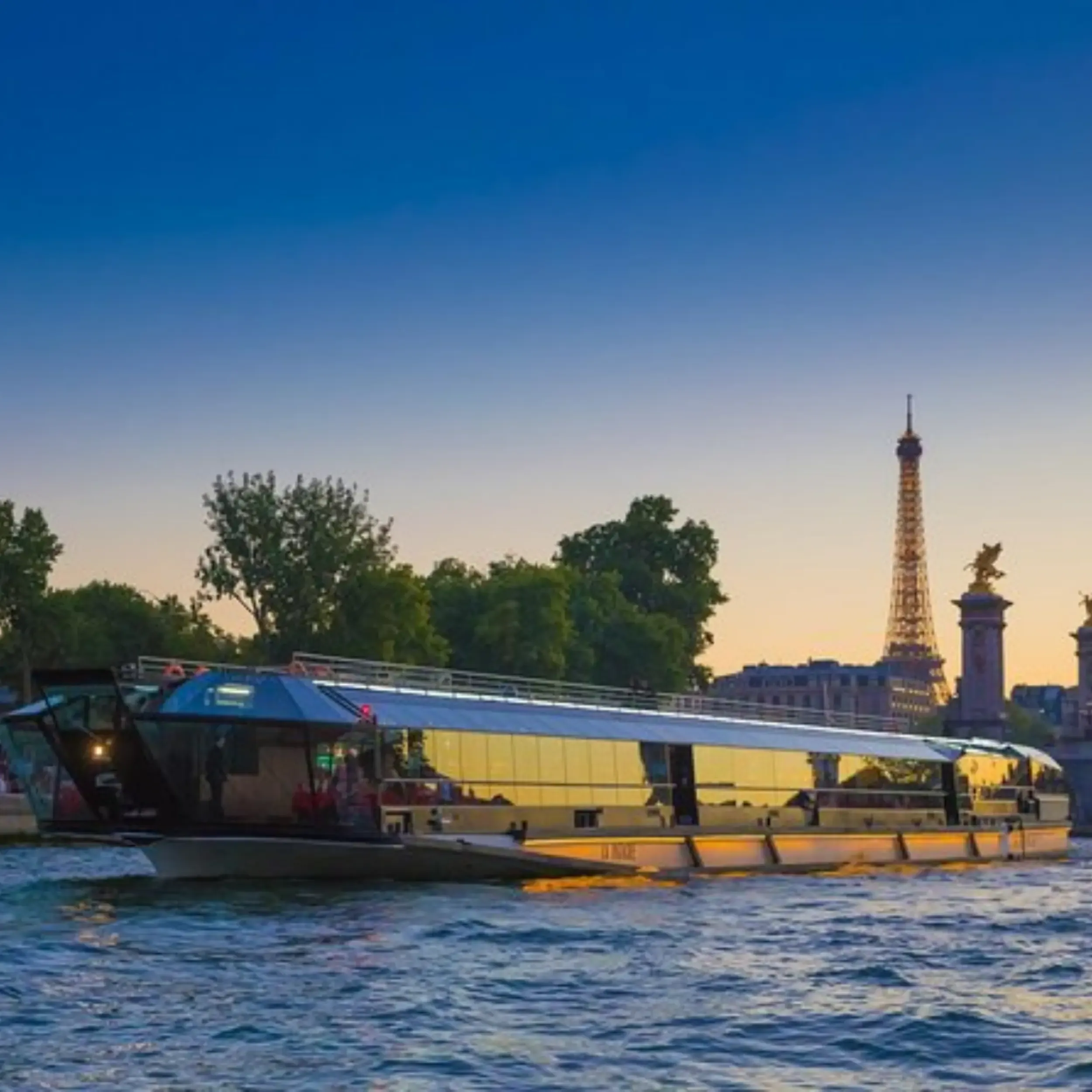 Boats on the Seine at sunset with the Paris skyline glowing